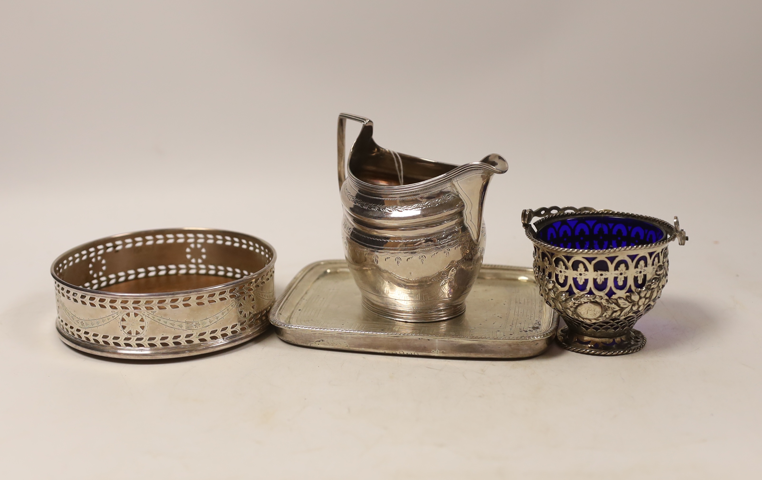A George III engraved silver helmet shaped cream jug, London, 1801, height 10.5cm, a small George III pieced silver sugar basket? (liner a.f.), London, 1770, a George III silver mounted teapot stand, London, 1808 and a s
